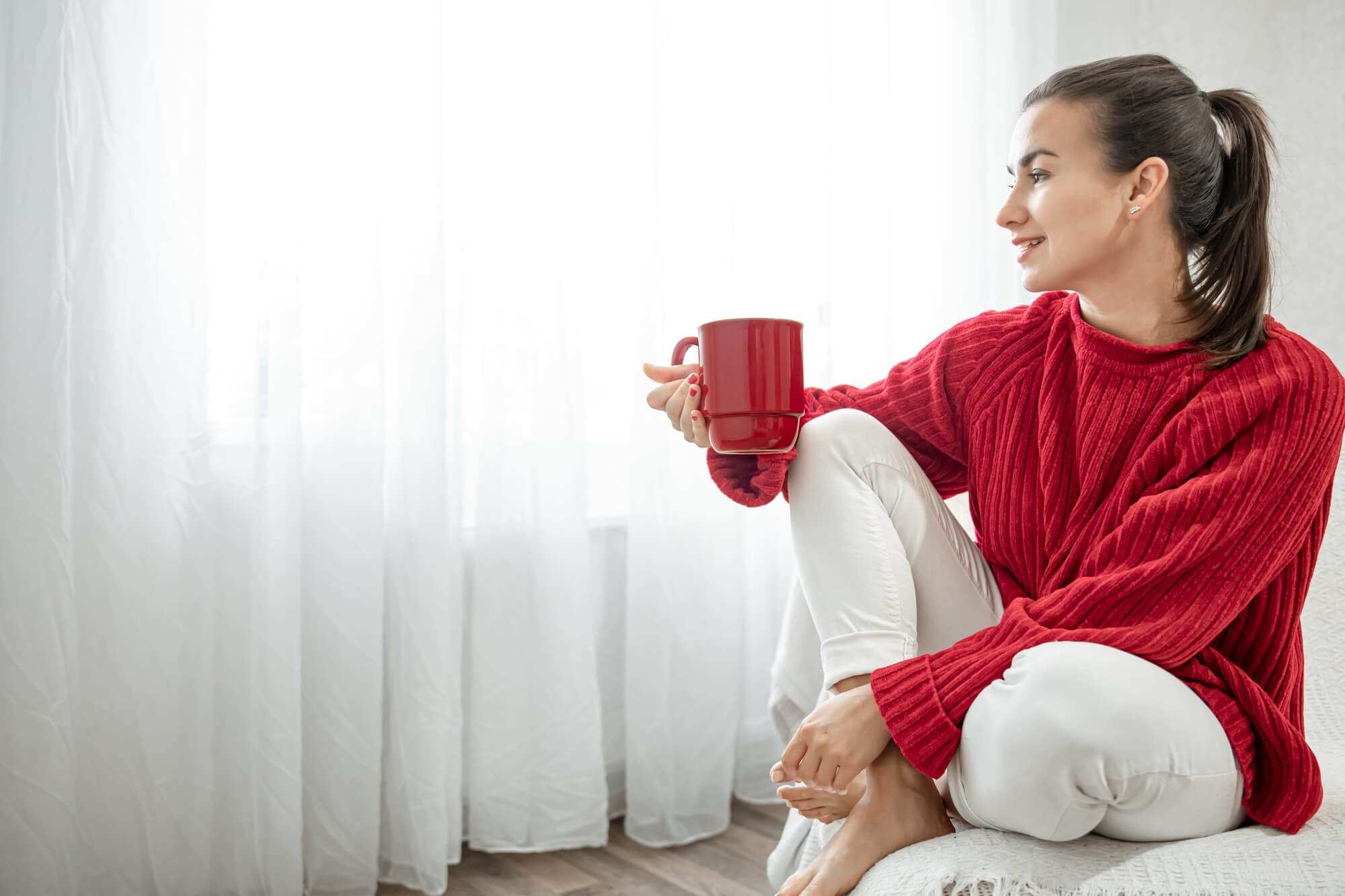 young-woman-with-red-cup-hot-drink-cozy-red-sweater-is-resting-couch-home-copy-space (1)